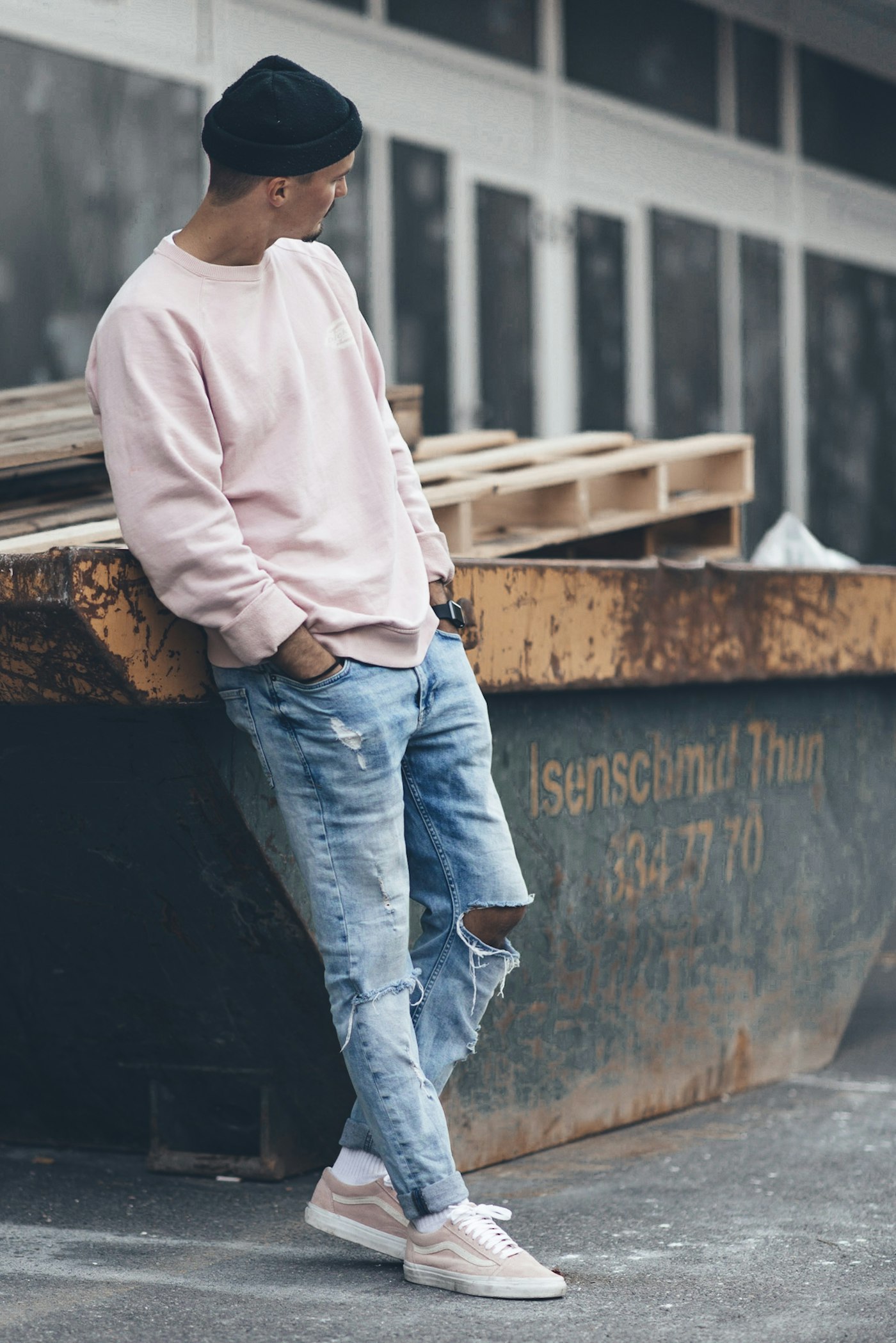Model in a pink crewneck and distressed denim